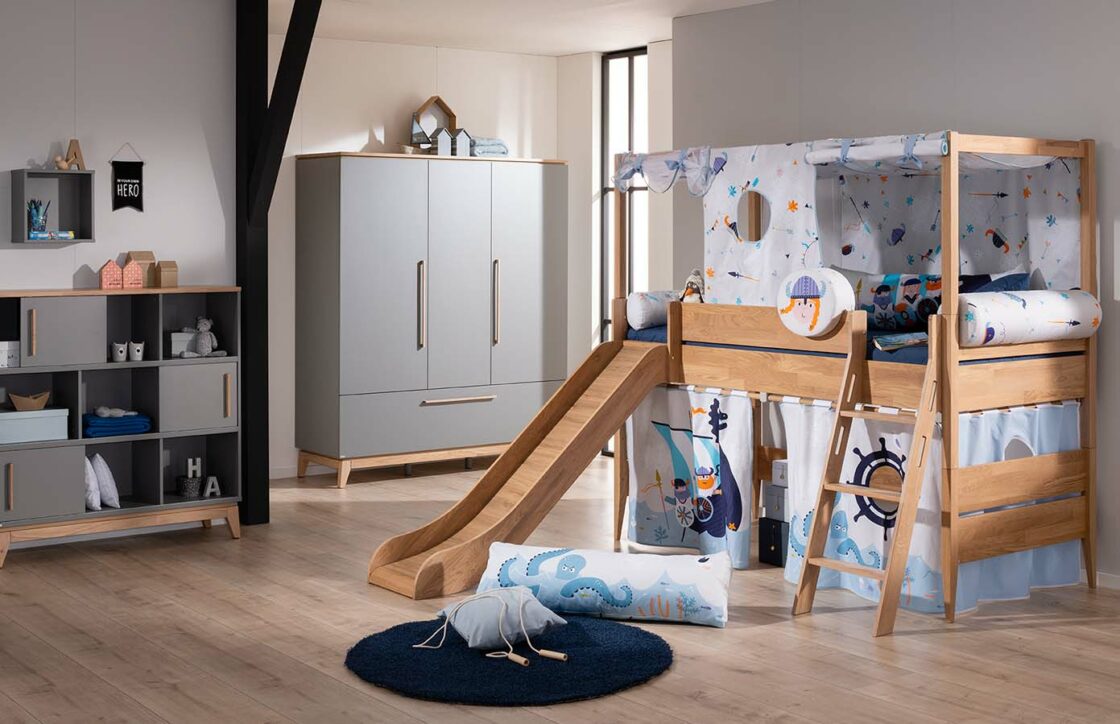 PAIDI Sten Spielbett, inklusive Spielzelt mit Wikinger Motiv, im Hintergrund steht ein PAIDI Sten Standregal und Kleiderschrank